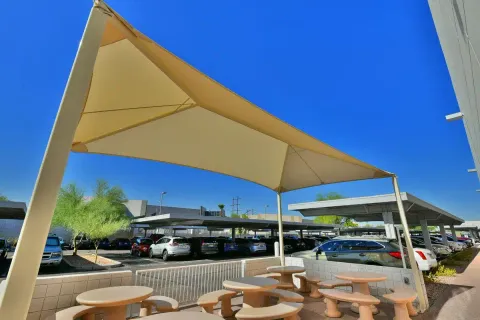 Framed canopy over outdoor tables beside a commercial building.