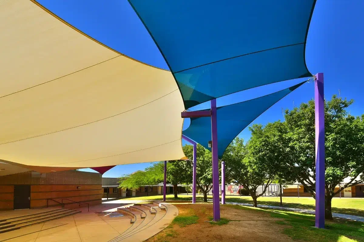 Yellow, blue and purple shade sails above outdoor gathering space at Coyote Trail