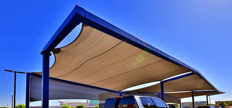 Beige shade-fabric panels within blue steel frames above a vehicle area at Dutch Bros, Val Vista