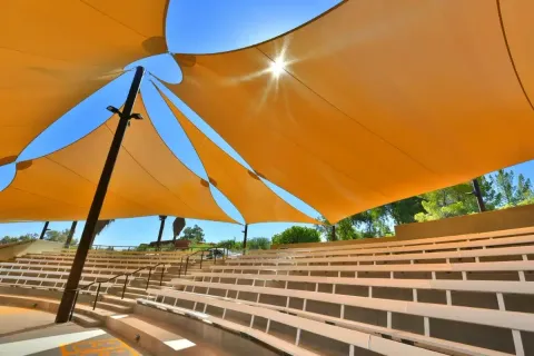 Yellow shade sails above tiered amphitheater seating.