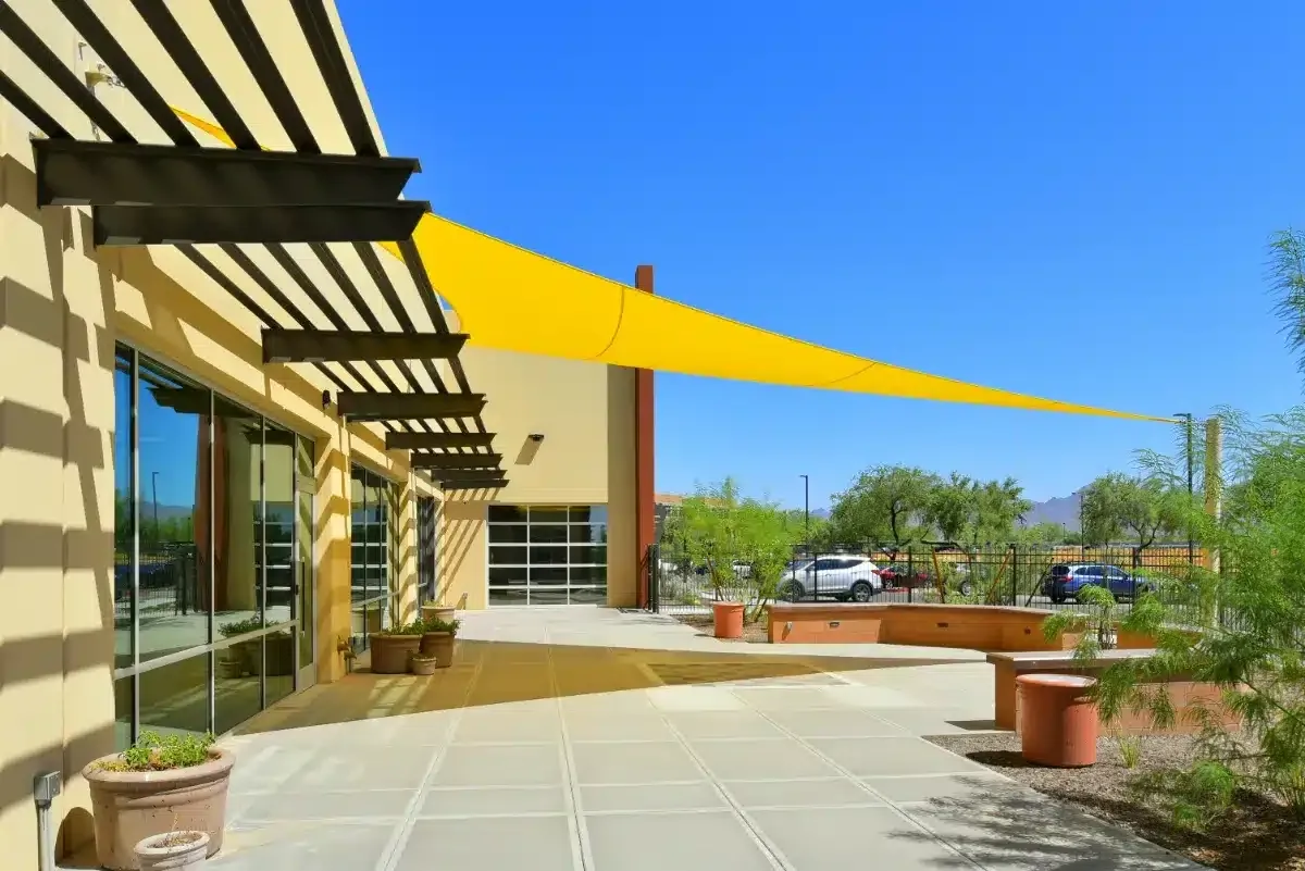 Yellow tensile shade structure across an Arizona commercial courtyard