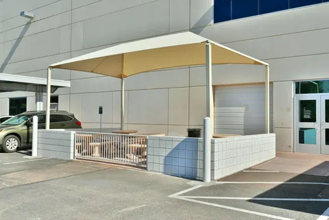 Four-post canopy beside a building entrance and outdoor tables.