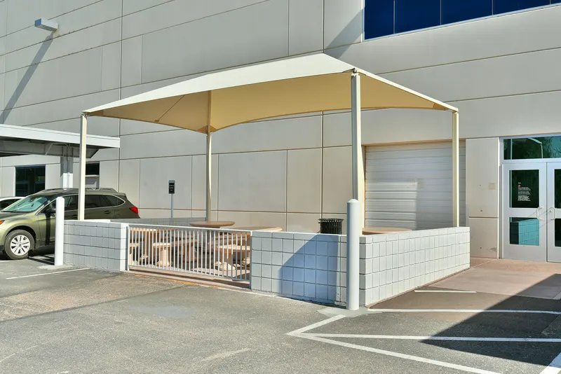 Four-post canopy beside a building entrance and outdoor tables.