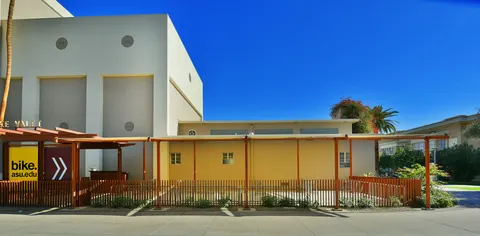 Shade panels along a fenced outdoor seating area.