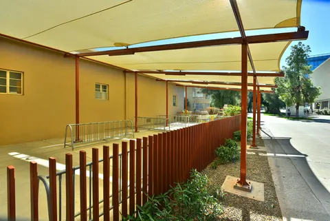 View beneath light-colored shade panels beside a building.