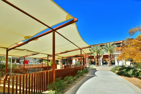 Repeated shade panels beside a campus walkway.