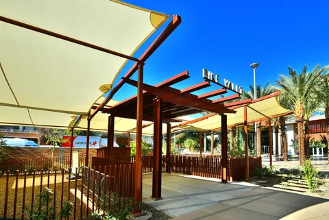 Overlapping shade panels and open framing above courtyard seating.