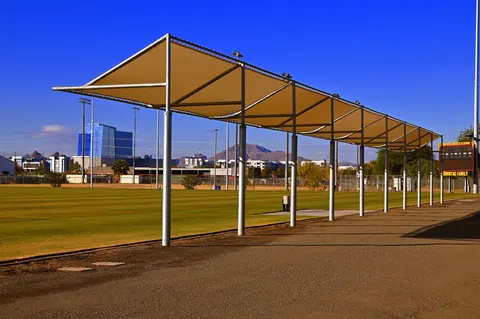 Long framed canopy beside a sports field.