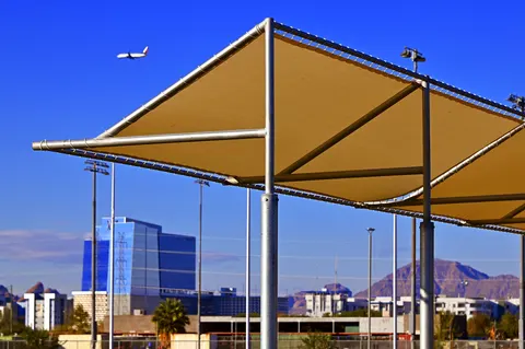 Close view of a framed canopy beside sports fencing.