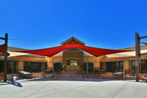 Red and dark shade sails above a fenced outdoor play area.