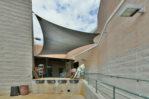 Wall-mounted shade sails above a narrow courtyard.