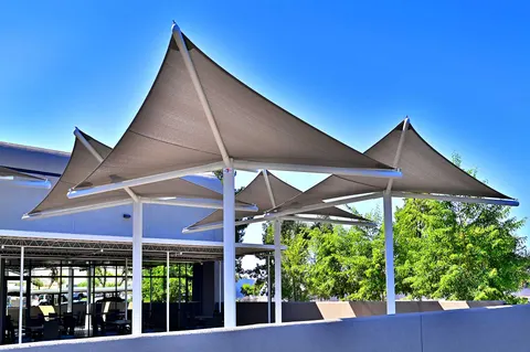 Repeated peaked umbrellas above a paved outdoor area.