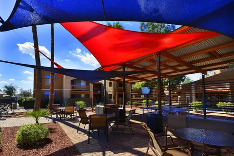 Blue and red shade sails above outdoor dining tables.