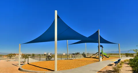 Blue shade sails on tall posts above a play area.