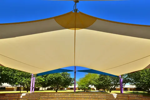 View beneath a broad light-colored sail above a gathering area.