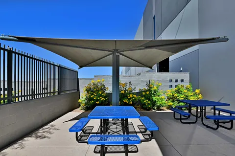 Peaked shade umbrella above outdoor picnic tables.