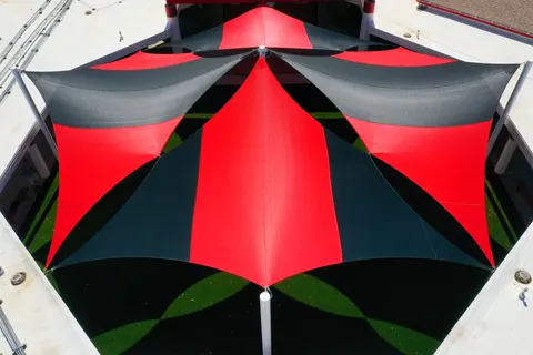 Overhead view of alternating red and dark peaked umbrellas.