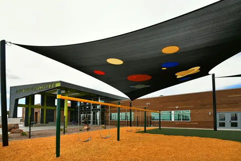Patterned shade sail above an outdoor play area.
