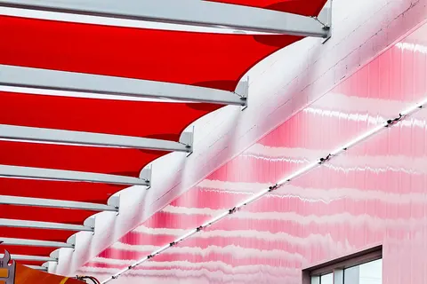 Red shade panels attached to curved brackets along a building.