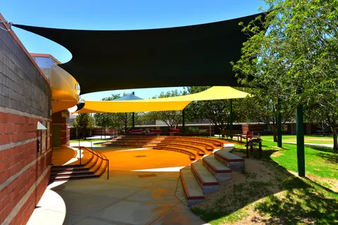 Dark and yellow shade sails above an outdoor amphitheater.