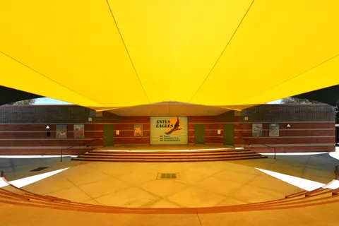 View beneath a yellow sail above an outdoor stage and seating.