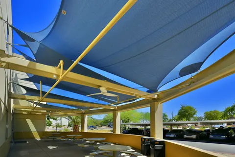 Blue shade panels and yellow framing above outdoor tables.
