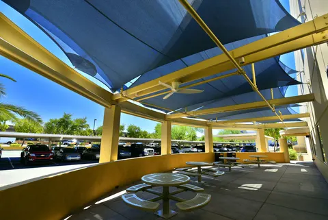 Shade panels above circular outdoor picnic tables.
