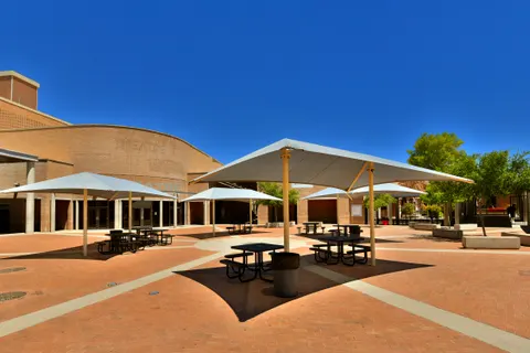 Repeated peaked umbrellas above courtyard picnic tables.