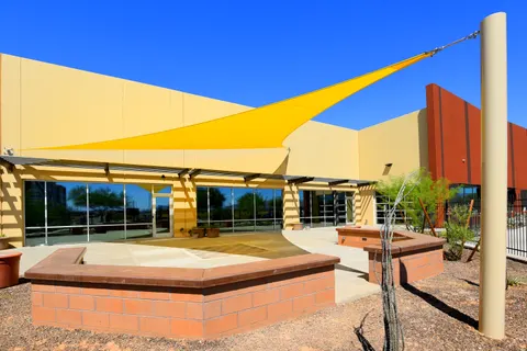 Yellow shade sails above a paved courtyard and low walls.