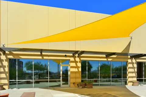 Side view of yellow shade fabric along a building facade.