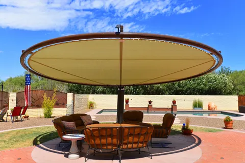 View beneath a round umbrella beside a residential pool.