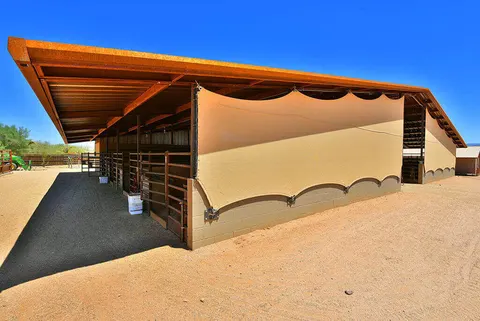 Vertical shade fabric along the side of a covered horse stall.