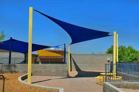 Blue and yellow shade sails above an enclosed outdoor area.