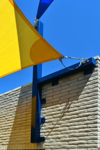 Close view of a shade-sail connection at a blue post.