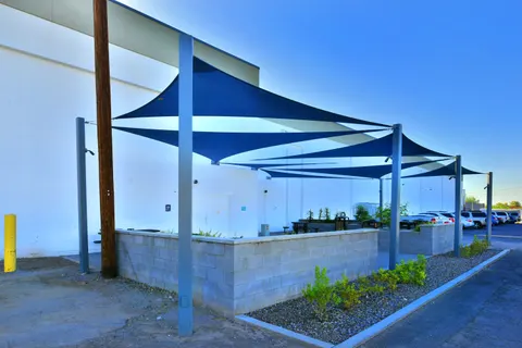 Repeated blue shade sails beside a commercial building.