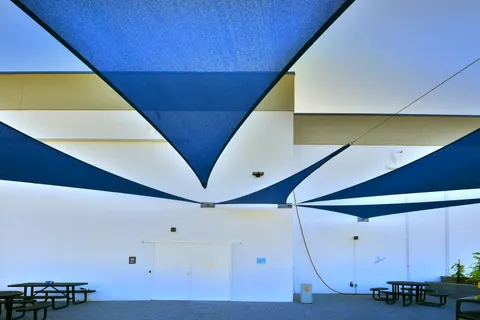 Upward view of blue shade sails above an outdoor patio.