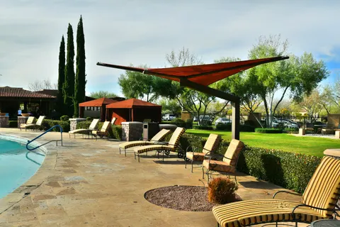 Red cantilevered shade umbrella beside poolside lounge chairs.