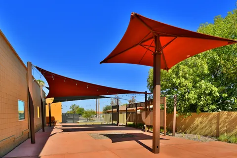 Red umbrella and triangular sails above an outdoor courtyard.