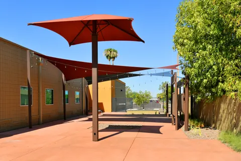 Red umbrella and shade sails beside a courtyard walkway.