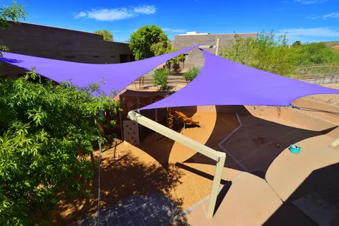 Purple shade sails surrounding paths and play areas.