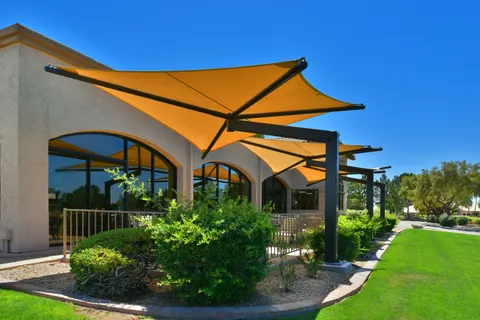 Yellow shade umbrellas beside a landscaped building terrace.