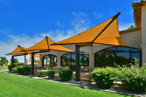 Yellow shade umbrellas above a landscaped outdoor gathering area.